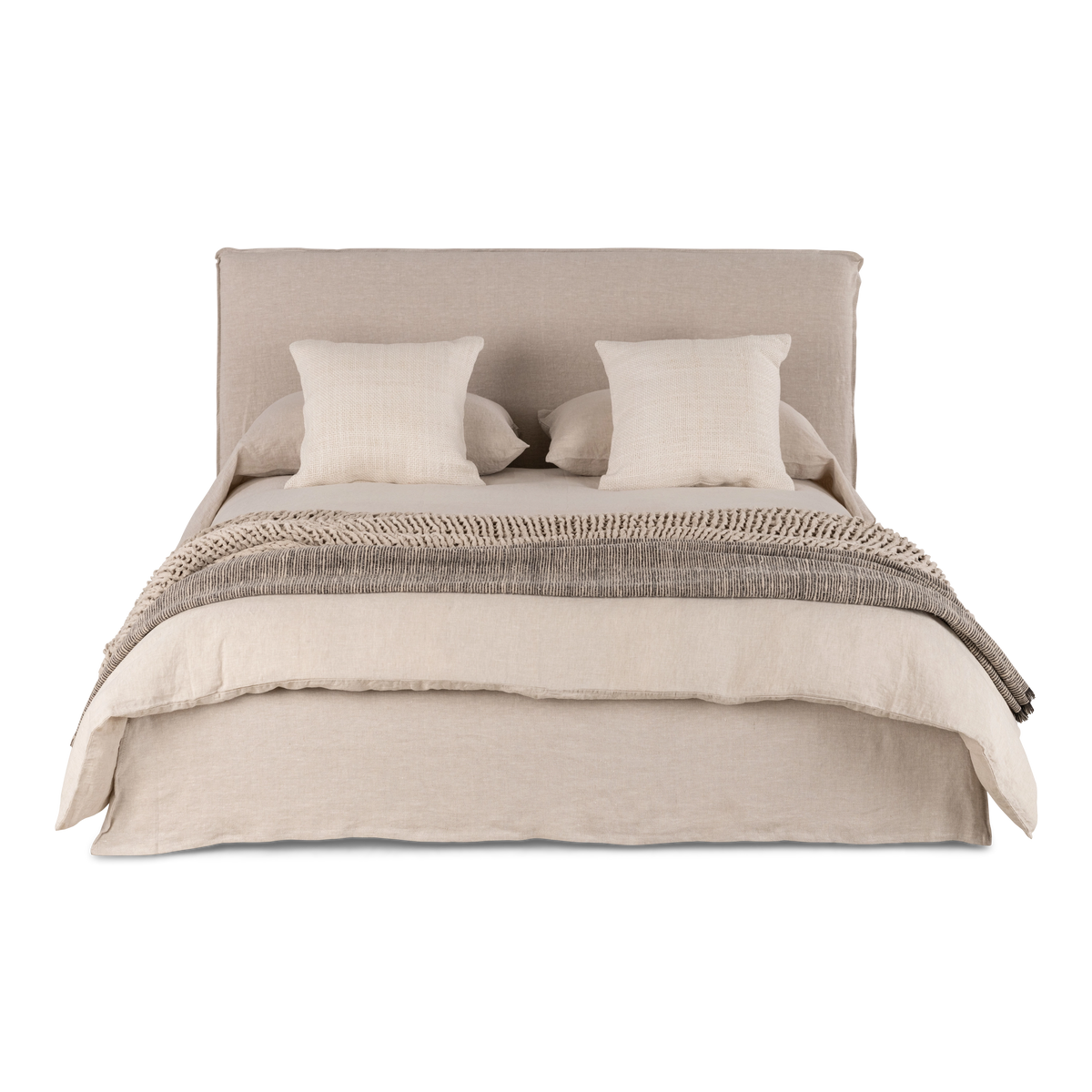 Muse Queen Bed from the front in natural linen, with a wide slipcovered headboard and skirted base, styled with two woven cushions and a knit throw.