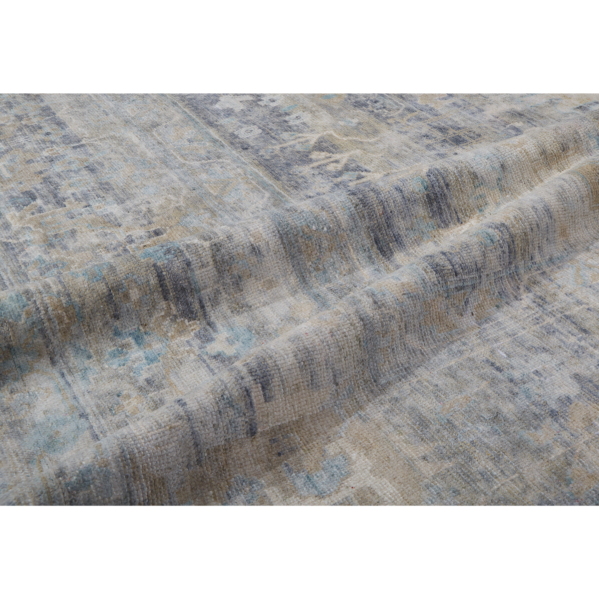A close-up of a textured area rug with an abstract distressed pattern in shades of blue, beige, gray, and brown.
