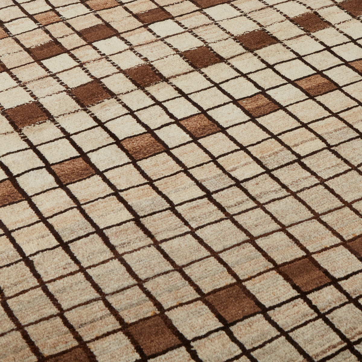 A close-up of a woven rug with a geometric checkered pattern in beige, cream, and brown.