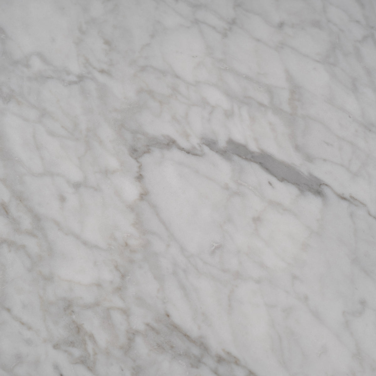 Aldo Dining Table close-up showing white Arabescato marble with soft gray veining across a smooth, honed surface.