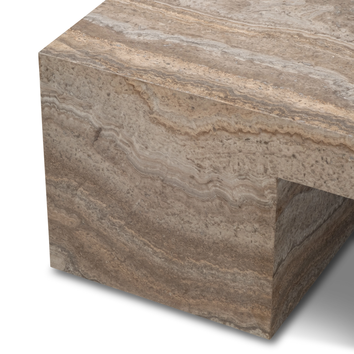 Close-up showing the corner of the Duvall Coffee Table in Taupe travertine, with wavy tan and cream banding on the slab edge and one block leg beneath.