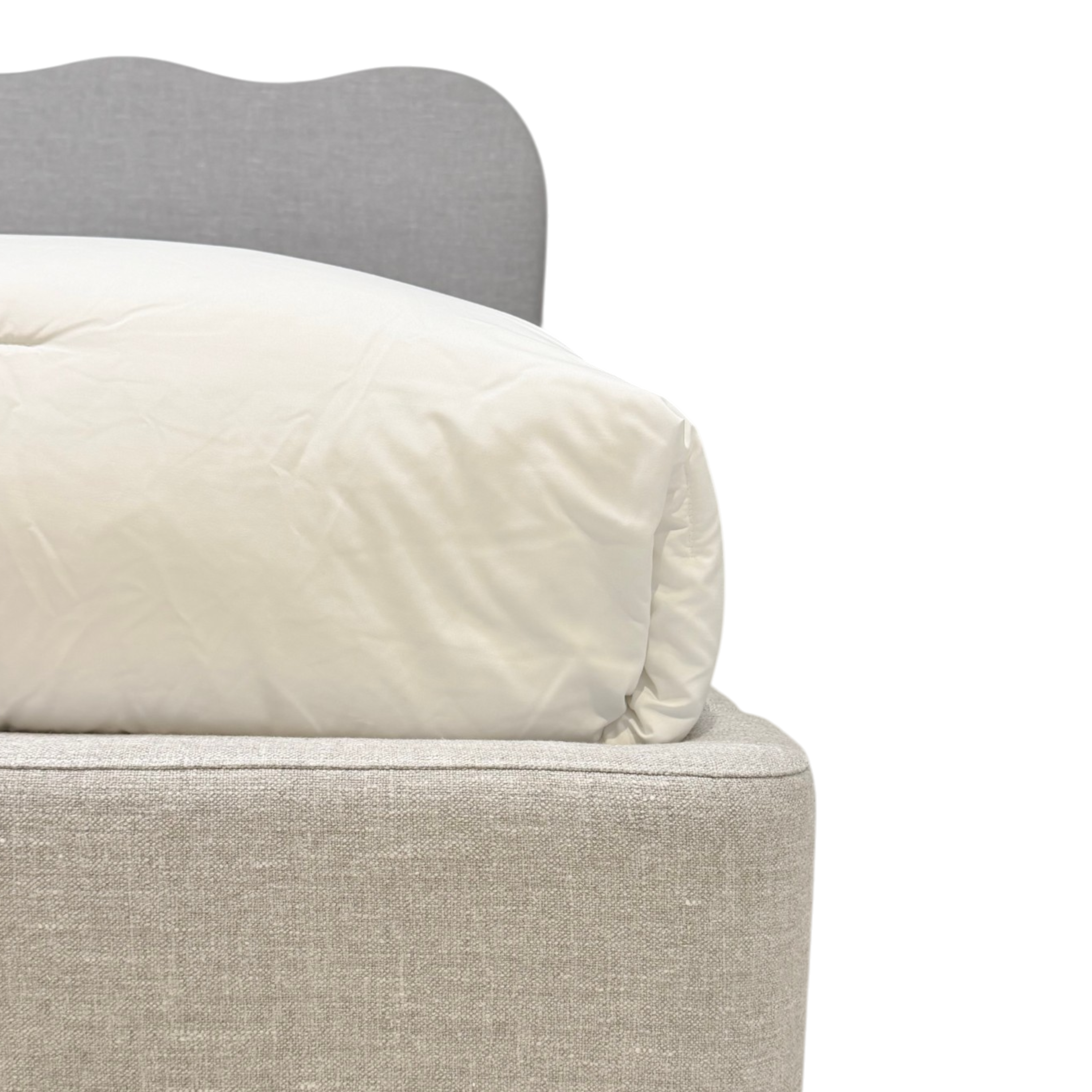 Sine King Bed a close-up of a bed corner showing a cream-colored duvet or comforter resting on a light beige upholstered bed frame, with a gray headboard partially visible against a white background.