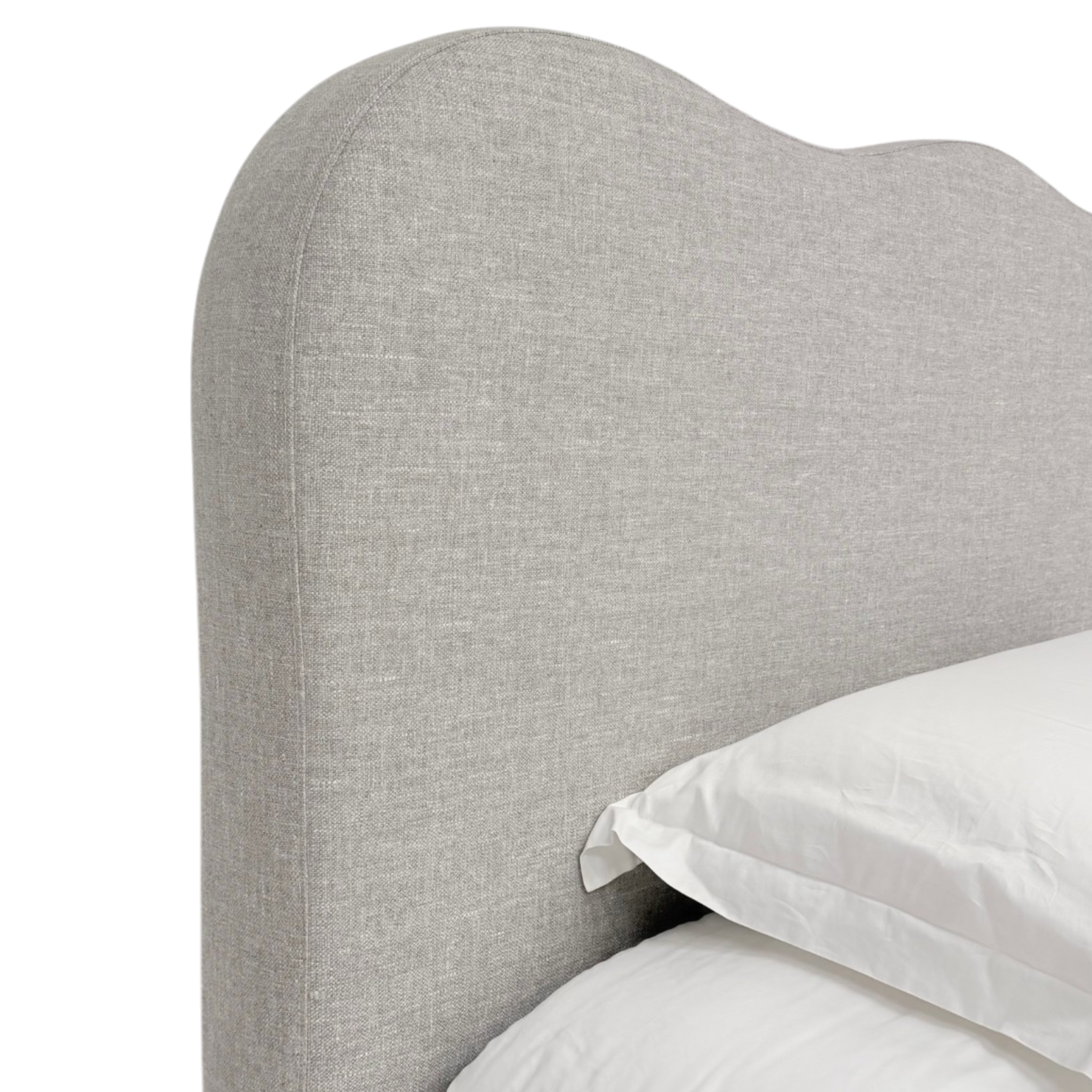 Sine King bed a close-up of a light gray upholstered headboard with a curved top edge, shown with white bedding and pillows against a white background.