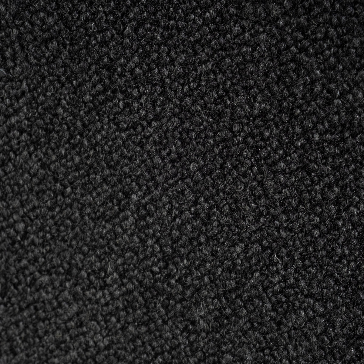 Macro close-up of the charcoal bouclé fabric on the Colonna Modular Sectional, showing deep black loops mixed with lighter gray flecks.