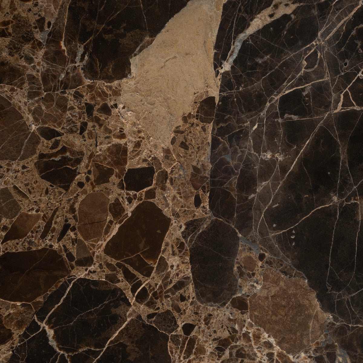 Close-up of dark brown Emperador marble texture showing a pale tan patch, cream veining and a fractured, mosaic-like pattern.