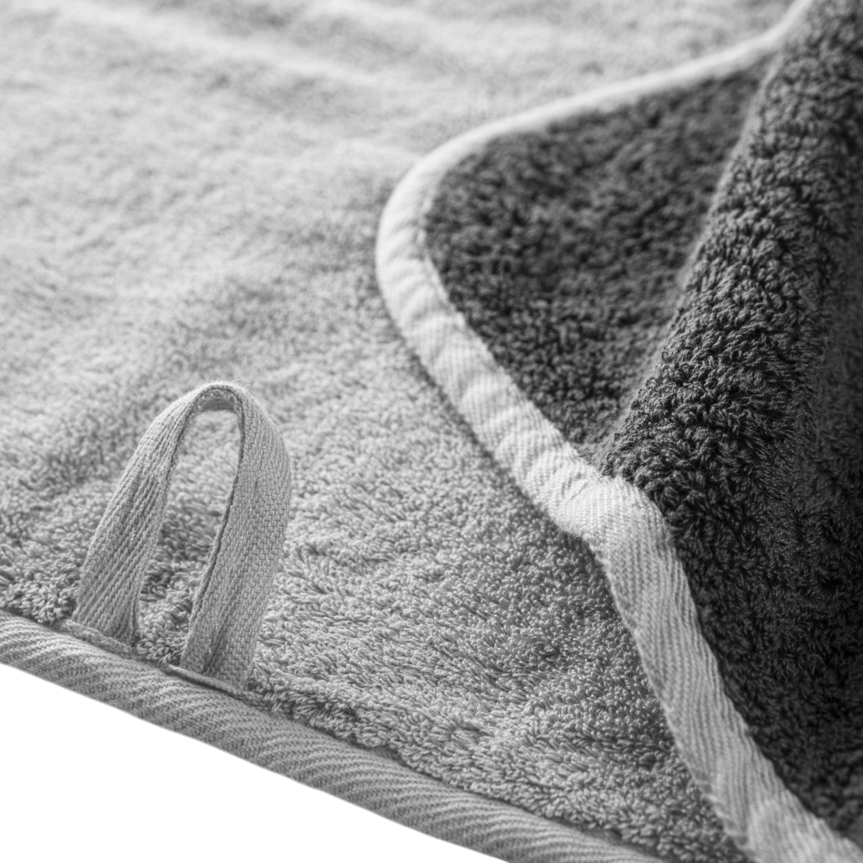 Close-up of the Bicolore Bath Towel in Storm/Silver, highlighting plush terry texture, pale bias binding and the contrasting double-sided finish.
