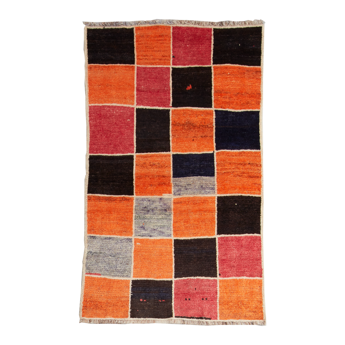 A square handwoven kilim rug featuring a patchwork design of orange, black, red, and blue geometric blocks, finished with a fringed edge.