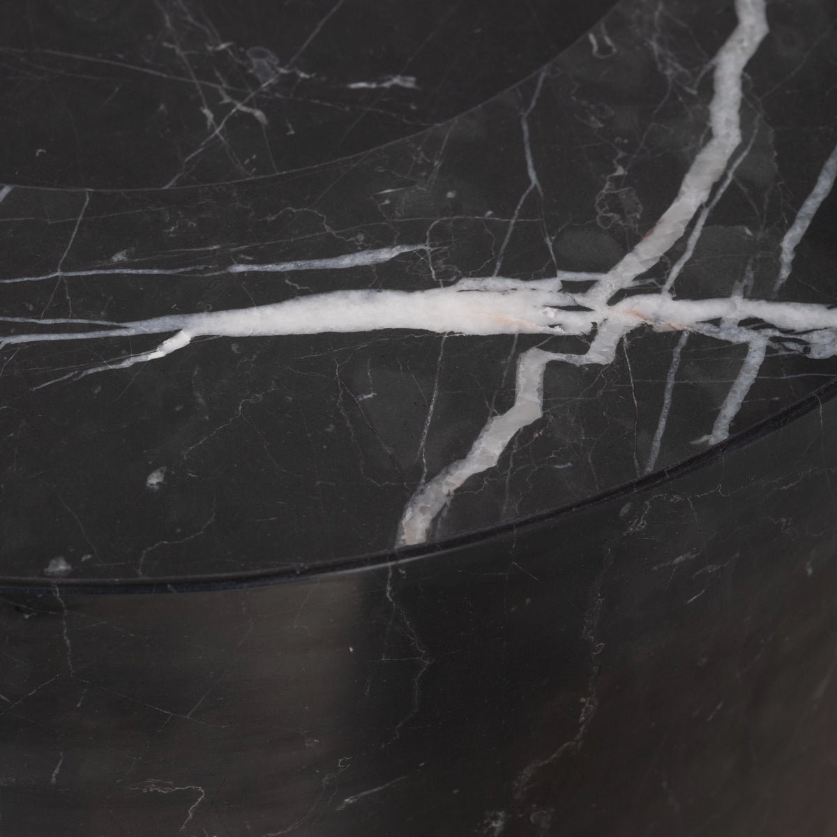 Shift Console Table close-up in black Nero Marquina marble, showing bold white veins crossing the rounded top edge above the curved leg.
