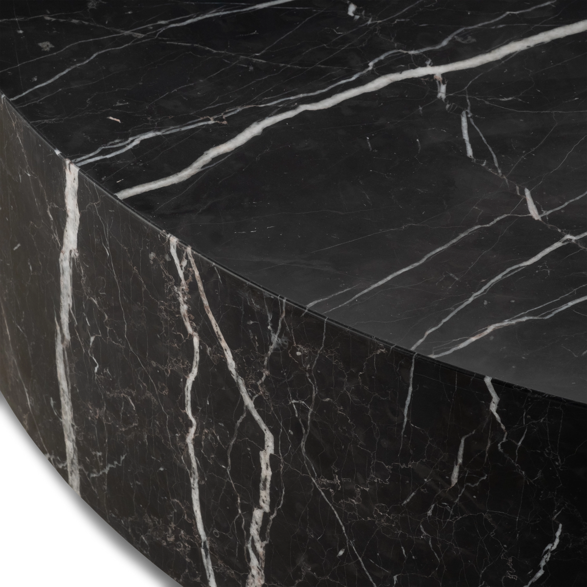 Close-up showing the rim of the Meta Round Coffee Table in Black Nero Marquina marble, with the clean edge where the honed top meets the curved side and fine white and tan veining.