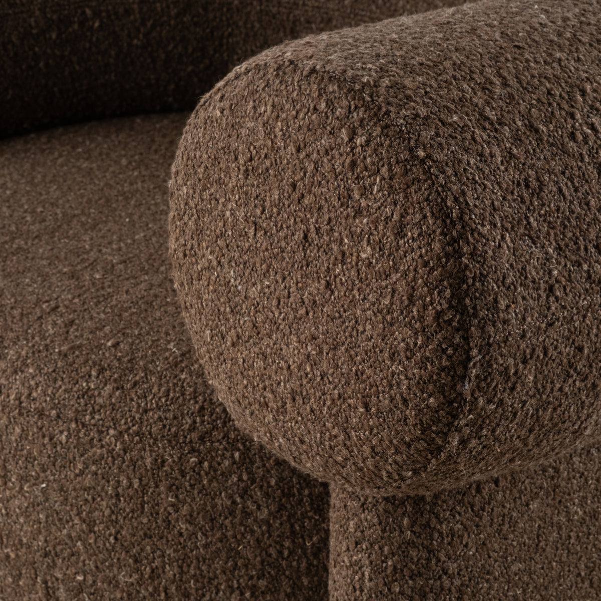Close-up showing the rounded barrel arm of the Embrace Lounge Chair in Espresso bouclé, with nubby looped texture and a subtle seam along the curve.